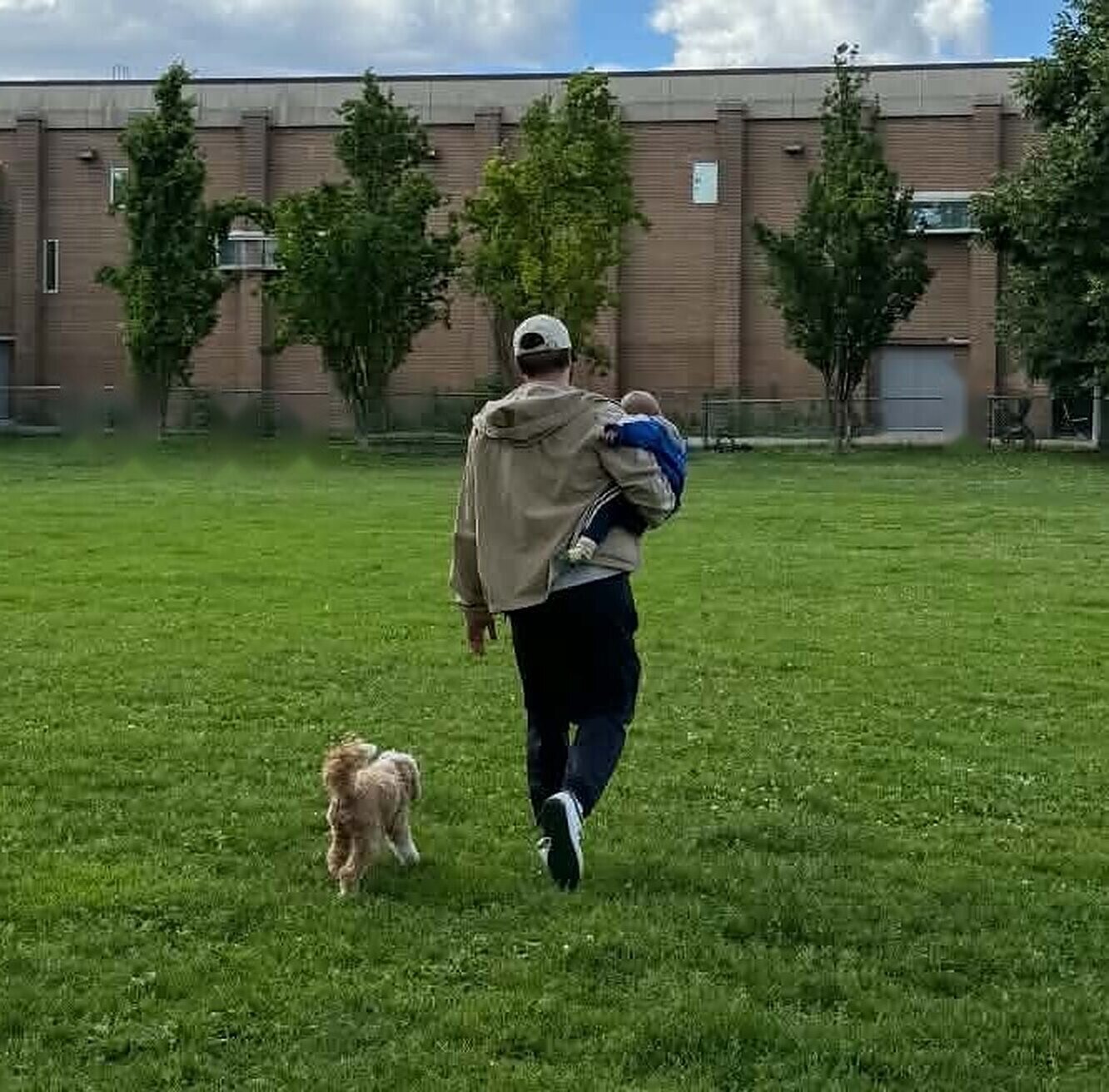 Tom walking across a park with his son and dog